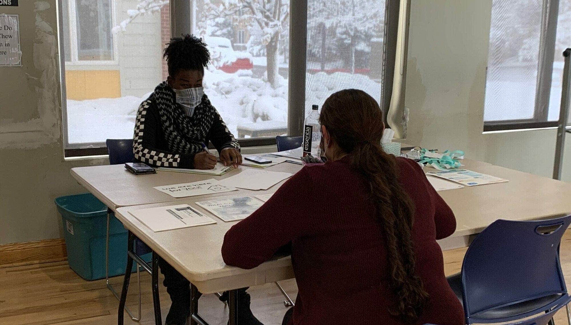 Caseworker conducting intake with tablet during severe weather, with snow visible through window